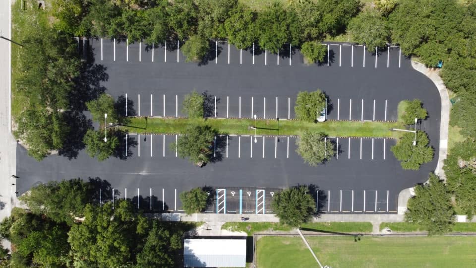Aerial view of a freshly sealcoated and striped commercial parking lot in Lee County, Florida